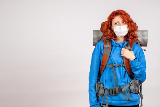 Front view female tourist going in mountain trip in mask with backpack