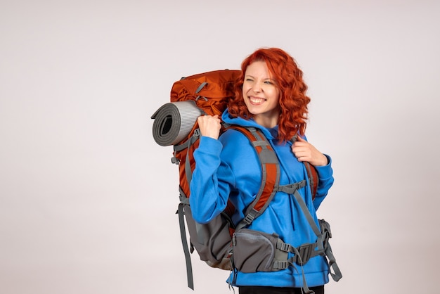 Turista femminile di vista frontale che va in viaggio di montagna con gioia di zaino