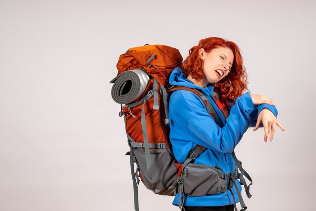 Front view female tourist going in mountain trip with backpack with pain in her arm