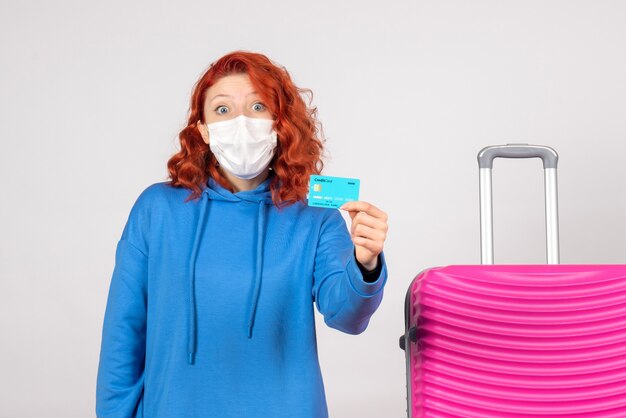 Front view female tourist holding bank card in mask