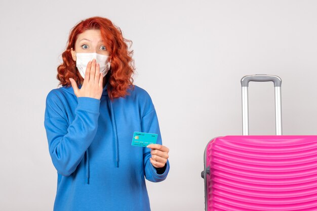 Front view female tourist holding bank card in mask