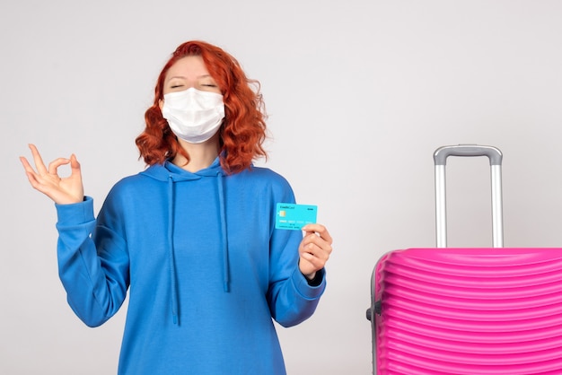 Front view female tourist holding bank card in mask