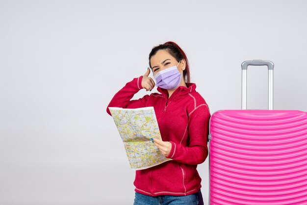 Front view female tourist holding map in mask on white wall