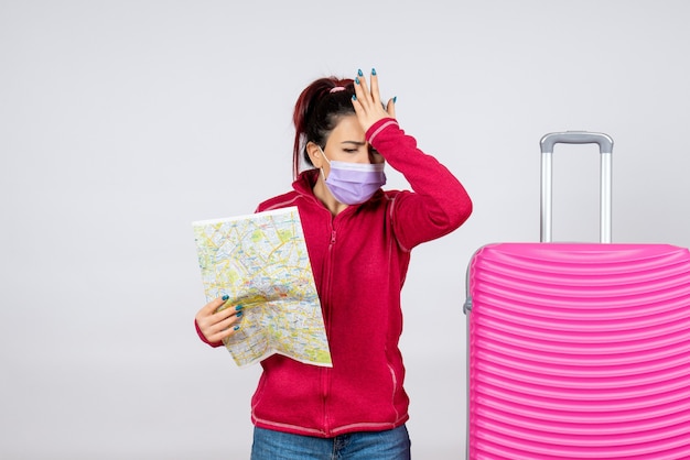 Front view female tourist holding map in mask on white wall