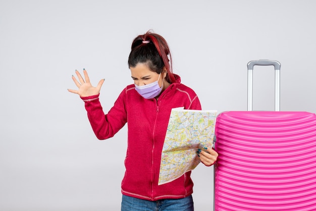 Front view female tourist holding map in mask on white wall