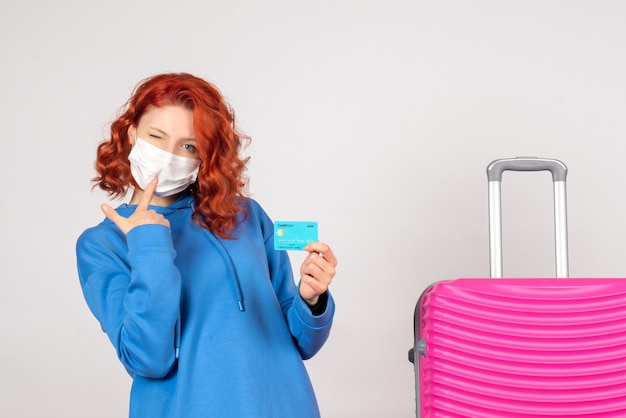 Front view female tourist in mask holding bank card