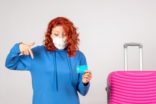 Front view female tourist in mask holding bank card