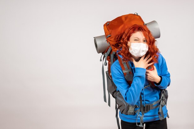 Front view female tourist in mask with backpack winking