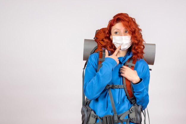 Front view female tourist in mask with her backpack