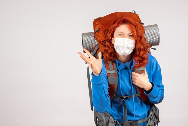 Front view female tourist in mask with her backpack