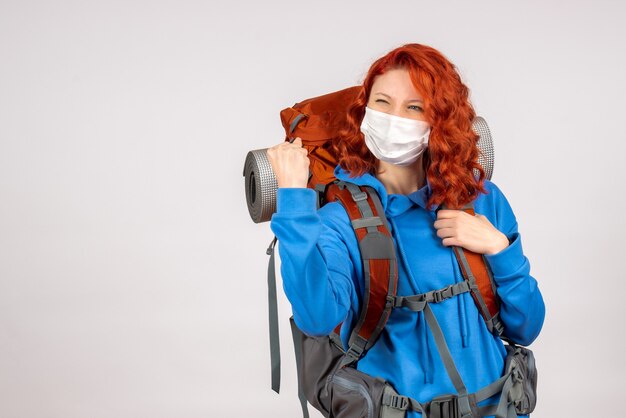 Front view female tourist in mask with her backpack