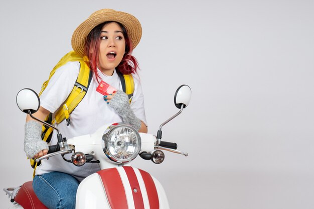 Front view female tourist sitting on motorcycle holding bank card light wall