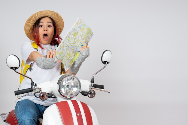 Front view female tourist sitting on motorcycle holding map white wall