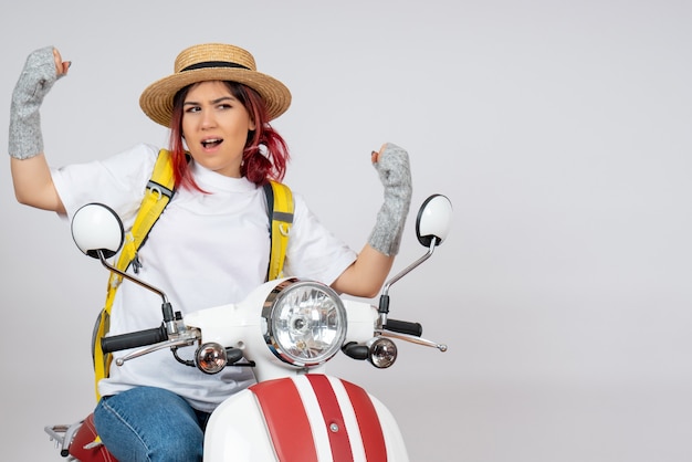 Front view female tourist sitting on motorcycle on white wall