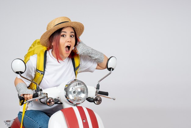 Front view female tourist sitting on motorcycle on white wall