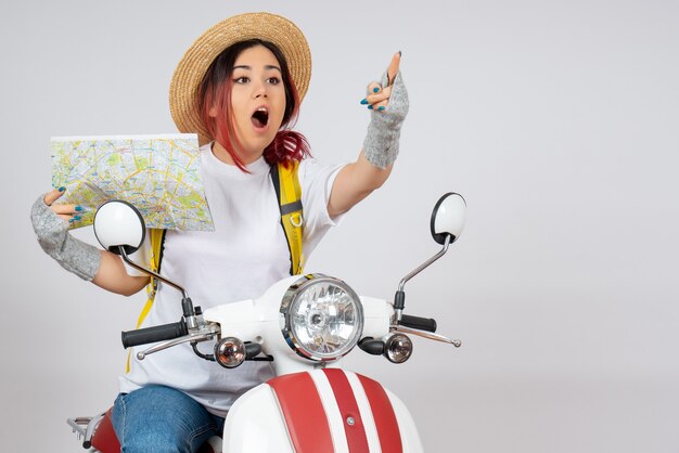 Front view female tourist sitting on motorcycle with map white wall