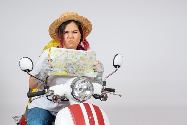 Front view female tourist sitting on motorcycle with map white wall