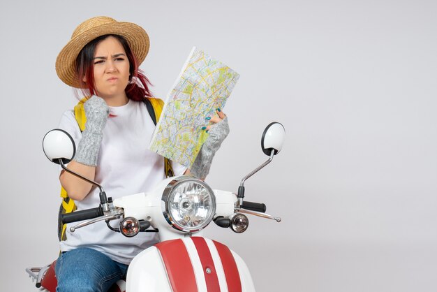 Front view female tourist sitting on motorcycle with map white wall