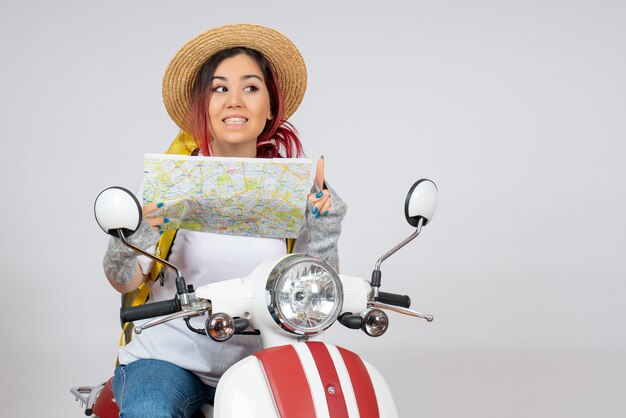 Вид спереди туристка, сидящая на мотоцикле с картой белой стене