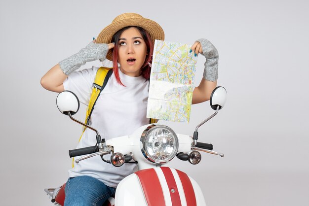 Front view female tourist sitting on motorcycle with map white wall