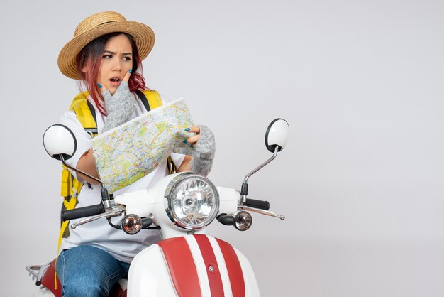 Front view female tourist sitting on motorcycle with map white wall