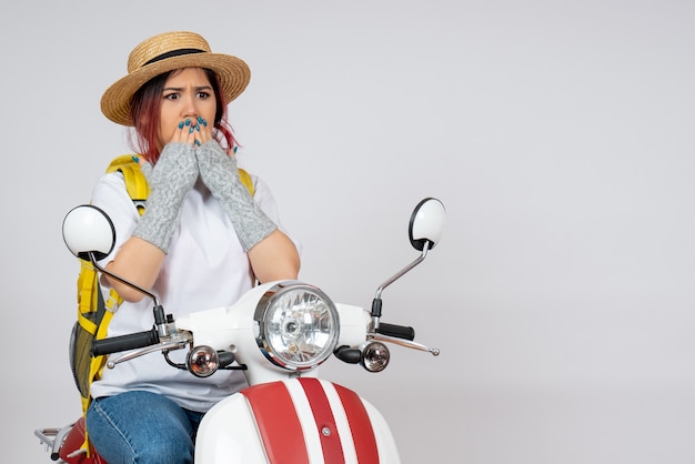 Front view female tourist sitting and posing on motorcycle surprised on white wall