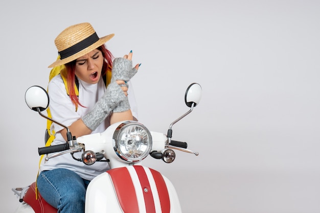 Front view female tourist sitting and posing on motorcycle on white wall v