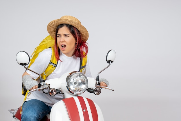 Front view female tourist sitting and posing on motorcycle on a white wall