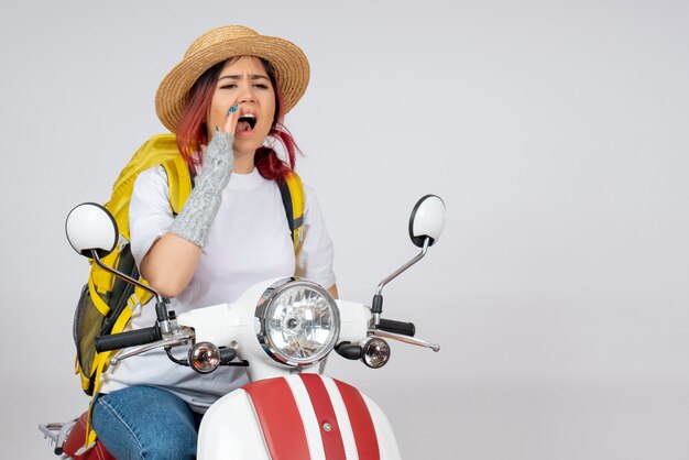 Front view female tourist sitting and posing on motorcycle on a white wall