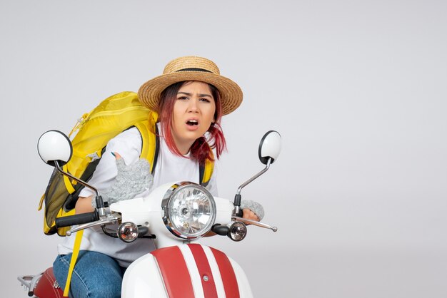 Front view female tourist sitting and posing on motorcycle on a white wall