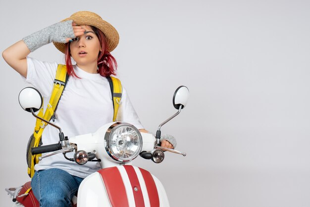 Front view female tourist sitting and posing on motorcycle on a white wall