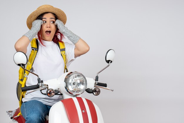 Front view female tourist sitting and posing on motorcycle on white wall 