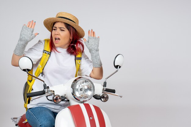 Front view female tourist sitting and posing on motorcycle on white wall 