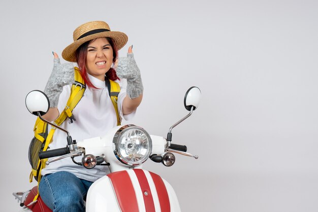 Front view female tourist sitting and posing on motorcycle on white wall