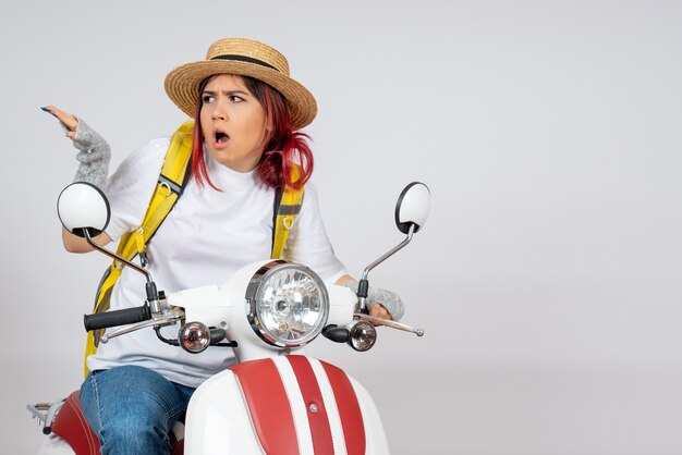 Front view female tourist sitting and posing on motorcycle on white wall