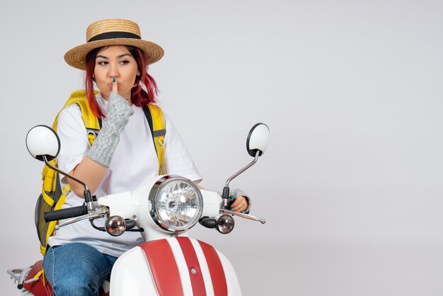 Front view female tourist sitting and posing on motorcycle on white wall