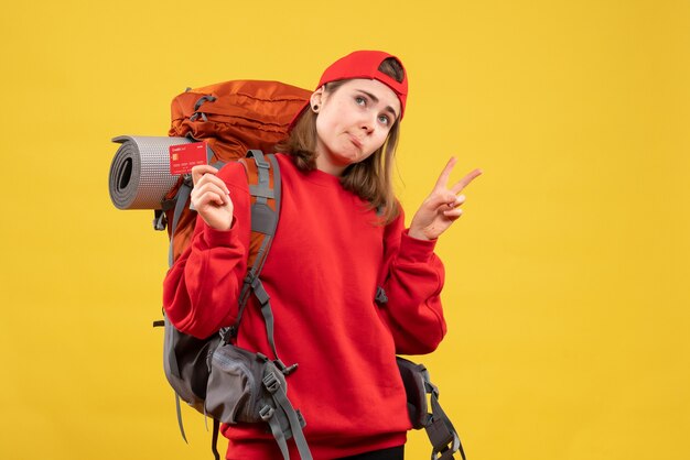 Front view female tourist with backpack holding discount card gesturing victory sign