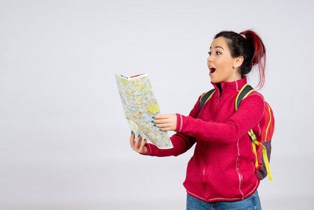 Free photo front view female tourist with backpack and map on white wall