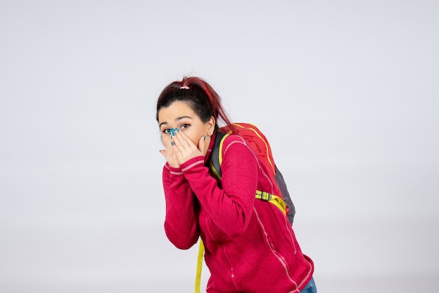 Front view female tourist with backpack on white wall