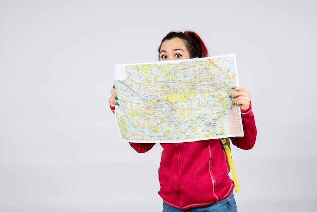 Front view female tourist with map in mask on white wall