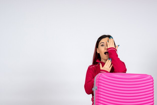 Front view female tourist with pink bag covering half of her face on white wall