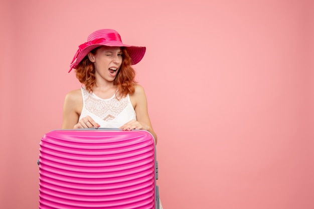 Front view of female tourist with pink bag on pink wall