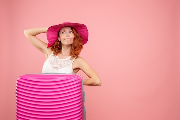 Front view of female tourist with pink bag on pink wall