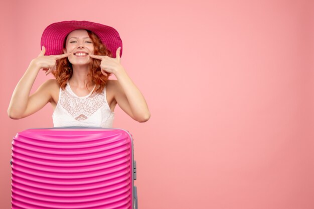 Front view of female tourist with pink bag on pink wall