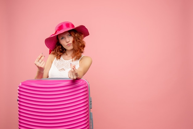 Front view of female tourist with pink bag on pink wall