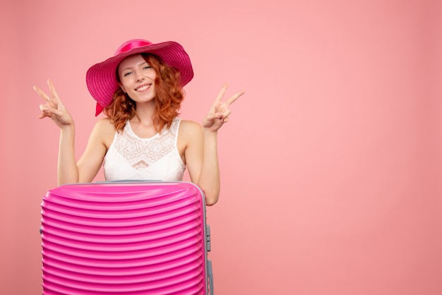 Vista frontale del turista femminile con borsa rosa sulla parete rosa