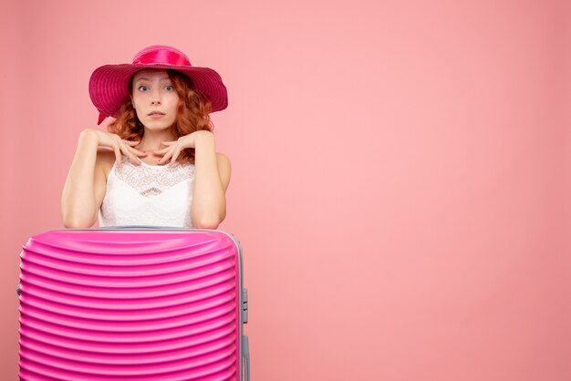 Front view of female tourist with pink bag on pink wall