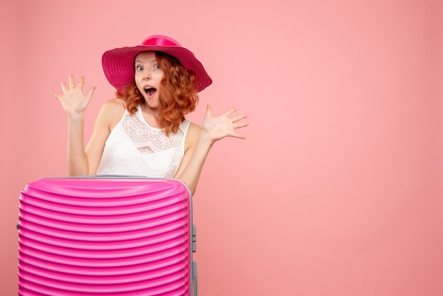 Front view of female tourist with pink bag on pink wall