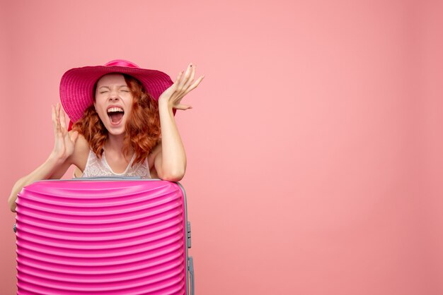 Front view of female tourist with pink bag on pink wall