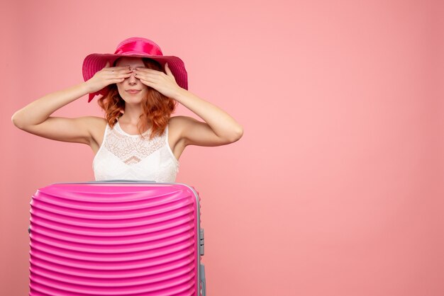 Front view of female tourist with pink bag on pink wall